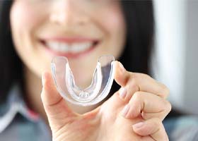 woman smiling and holding mouthguard