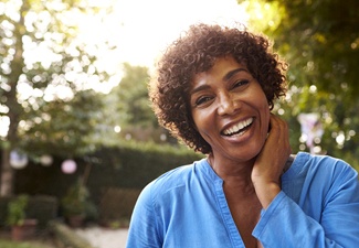 person smiling with their hand rested against their face