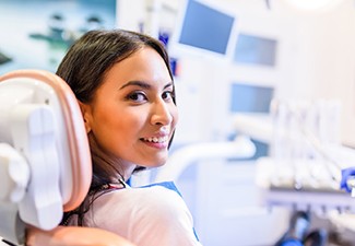 Young woman sitting in dental chair and smiling
