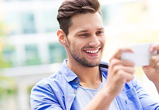 Smiling man sitting and looking at his phone