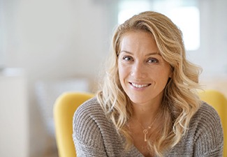 Woman in sweater sitting down and smiling