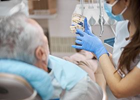 a dentist showing a patient a dental implant model 