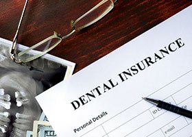 a blank dental insurance claim form with a pen sitting on top of it