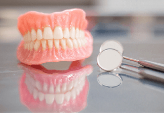 Dentures in Leawood, KS sitting on table next to dental mirror