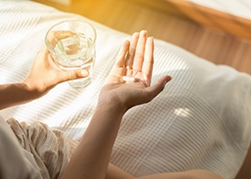 person taking pain medication after dental implant placement