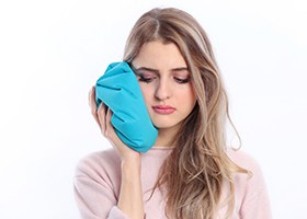 woman placing ice pack on sore jaw
