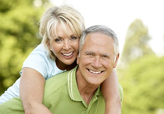 An older couple with dental implants in Leawood smiling outside