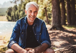 An older man with dental implants in Leawood smiling outside