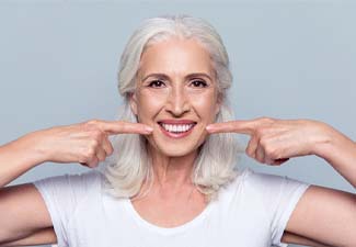 patient smiling and pointing to dental implants