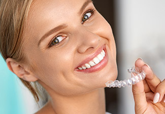 woman smiling while holding invisalign