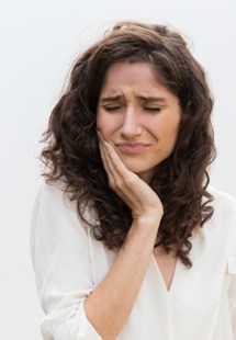 Woman rubbing her jaw and looking uncomfortable 
