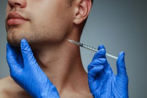 dentist administering facial filler into the jaw-area of a patient