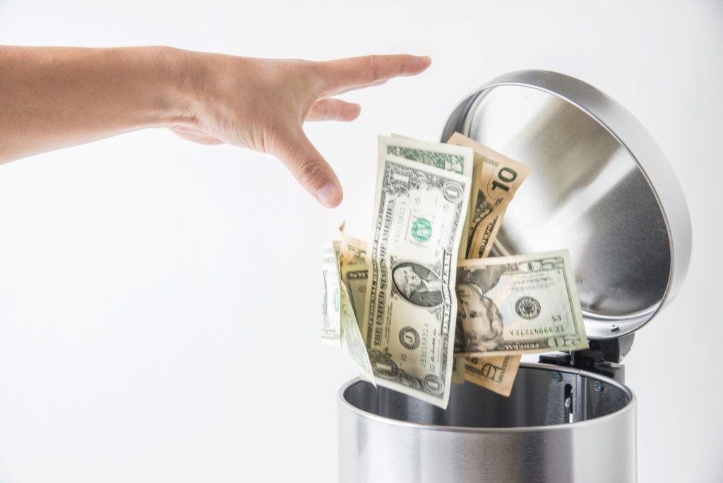 Closeup of person throwing away money in the trash