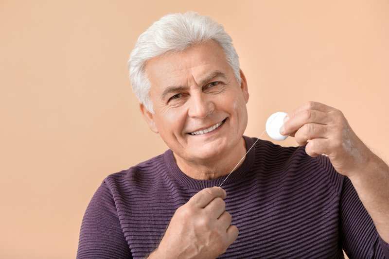 Senior man flossing dental implants